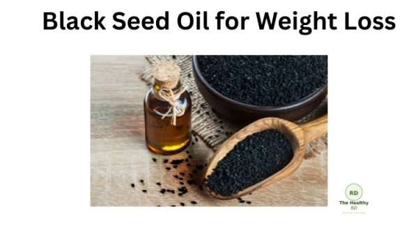 Bottle of black seed oil with loose black seeds and a wooden scoop on a rustic surface, illustrating a weight loss remedy.